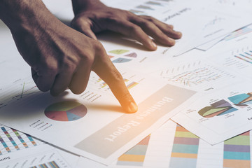 Close of hands of business men are working on a business report.