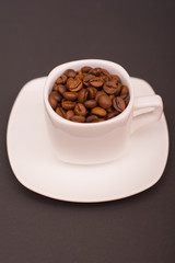 Coffee beans in a white cup on a dark background