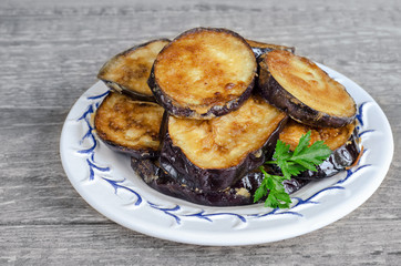 Fried eggplant, on the plate and a gray wooden background