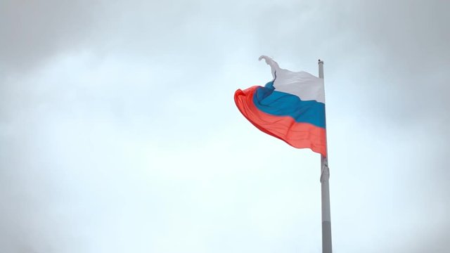 Russian flag on the flagpole waving in the wind against a blue sky with clouds. Slow motion, high speed camera, 250fps