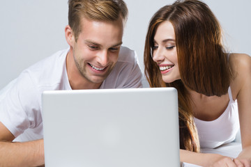 Couple using laptop, on bed
