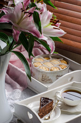 Still life with lilies, tea and desserts in shades of pink.