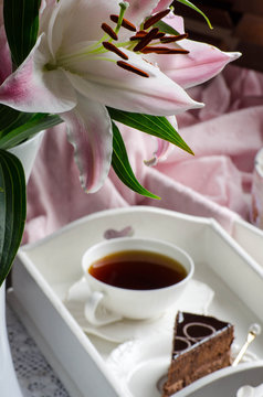 Still life with lilies, tea and desserts in shades of pink.