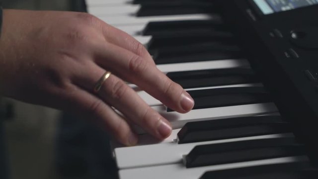 Man fingers on the synth electronic musical instrument close up details. Guy hand playing strums a chord on the synthesizer. Amr on the musical keyboard. performs at a concerto or rehearsing in the