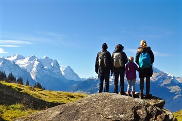 Wanderer - Familie,  stehen auf Felsen und geniessen den Blick und Aussicht auf die Schneeberge. Schneebedeckte Berge im Hintergrund, Schweiz - obrazy, fototapety, plakaty