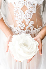 Gentle female hands holding a huge white flower, lace cloth covered body on the background