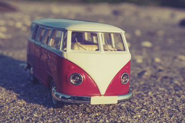 travel concept with classic van miniature on sandy beach over bl