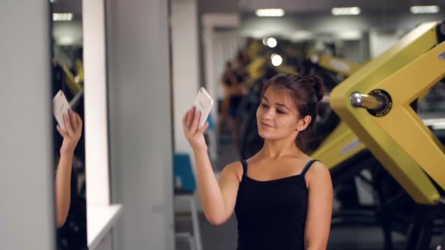 Sporty girl smiling at camera making selfie picture at gym. HD.