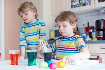 Two little blond kid boys coloring eggs for Easter holiday