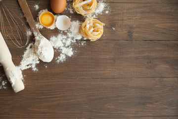 Cuisine composition with fettuccine cracked eggs,kitchenware, flour.