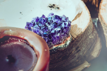 Purple amethyst stone with candles on wooden background. Esoteric, yoga, meditation, spiritual,...