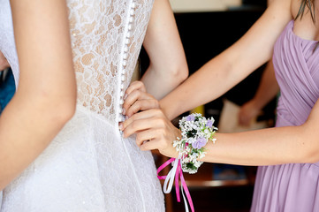 bridesmaid helps the bride to wear dress