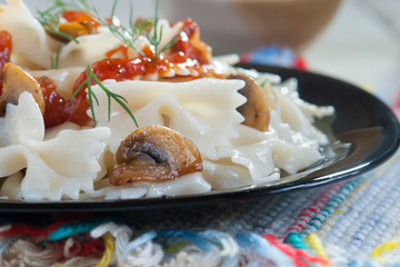 Farfalle Pasta with mushrooms on white plate and tomato sauce