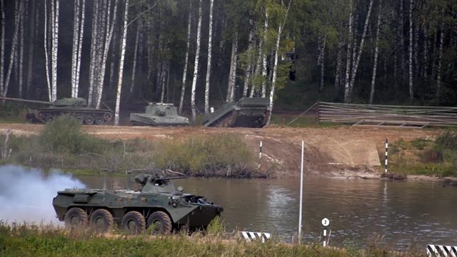 Armoured military vehicles going to swim across the river, and btr moving on a dirt road on military exercises. Includes audio. Contains audio