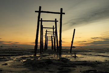 amazing tropical sunset background, wooden structure on the muddy beach
