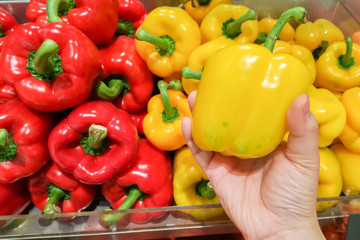 Housewife is shopping Ripe Yellow and Red Peppers in Vegetables market.