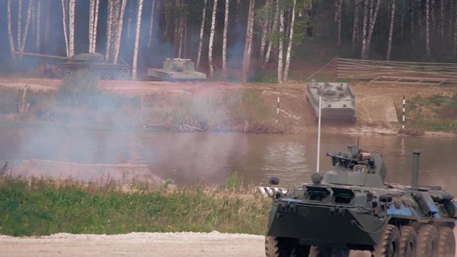 Armoured military vehicles going to swim across the river, and btr moving on a dirt road on military exercises. Includes audio. Contains audio