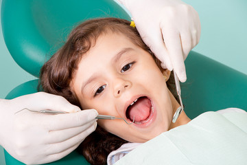 Dentist examining little girl's teeth at dental clinic 