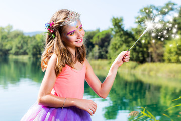 Little princess with magic wand at lake.