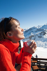 femme au sommet des montagnes avec un café sur une terrasse dans la neige