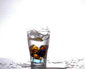 glass with multi-colored ice and water splashes