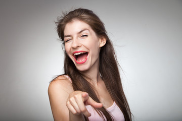 Flirtatious girl pointing on camera and winking.