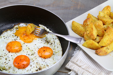 Fried eggs and a plate with sandy potatoes.