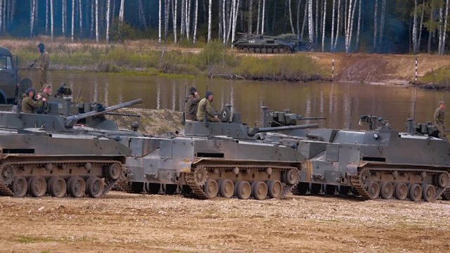Armored military BMP and soldiers on the board, successful cross the river by swimming. Quadrocopter shooting 