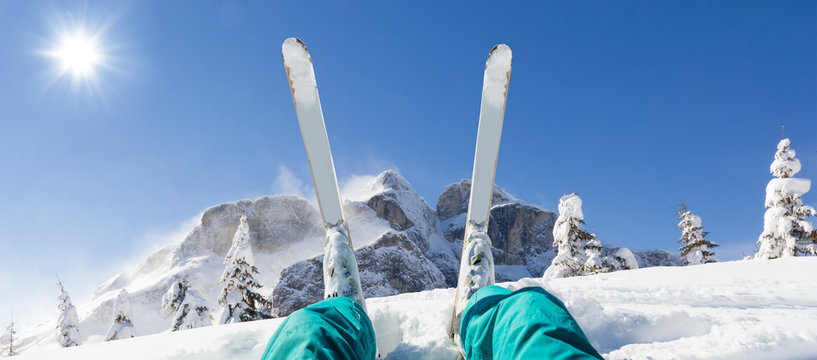 Detail of alpine skier legs, watching the valley panorama