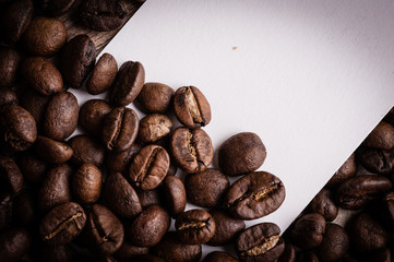 roasted coffee beans with black paper on wooden background, can be used as a background