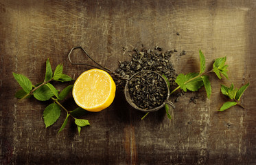 Dry tea with mint and lemon on wooden table