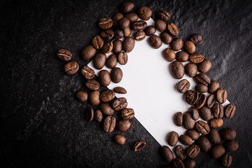roasted coffee beans with blank paper on dark background, can be used as a background
