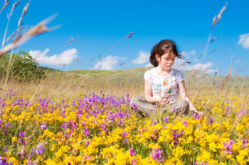 Girl sitting in a field of wild flowers