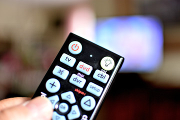 TV remote control closeup with television in background