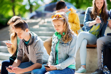 teenage friends with smartphones outdoors