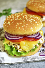Cheeseburger with chicken salad and fresh vegetables.