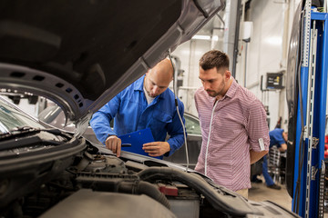 auto mechanic with clipboard and man at car shop