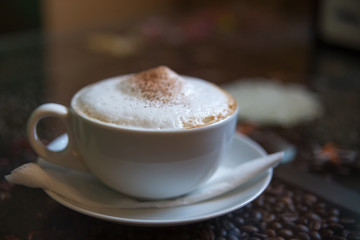 Cup of cappuccino on the table. in a dark café. soft focus.