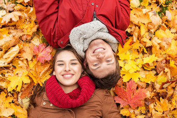 close up of smiling couple lying on autumn leaves