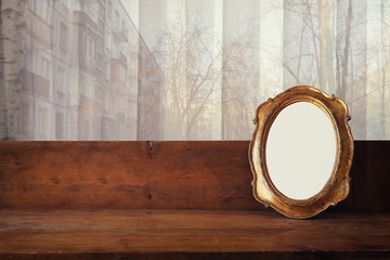 Golden old blank frame on window sill and urban view