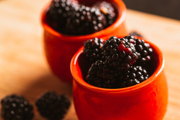 Blackberries in a cup on blurred background of wooden planks