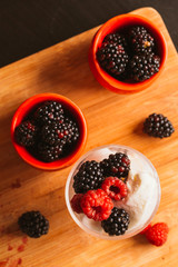 Blackberry ice cream in a cup and  glass on  background of wooden boards   blurred green