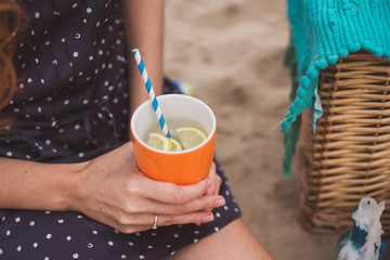 Romantic dinner on the riverside. Closeup of a young caucasian woman holding an orange glass of water in her hands. Engagement ring on her finger.