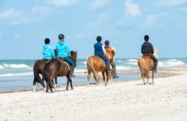 Kinder reiten mit Ponys am Strand