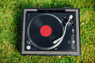 turntable with LP vinyl record on green grass background