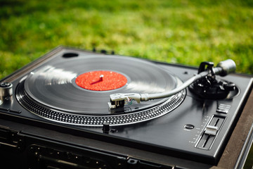 turntable with LP vinyl record on green grass background