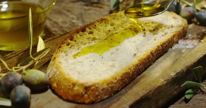 Genuine Italian organic oil cold pressed in slowmotion falls on organic bread. concept of nature and healthy food, healthy and natural. fresh olives and Tuscan Italian oil