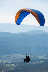 Paragleiter in der Luft über einem Tal - obrazy, fototapety, plakaty