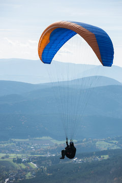 Paragleiter in der Luft &uuml;ber einem Tal