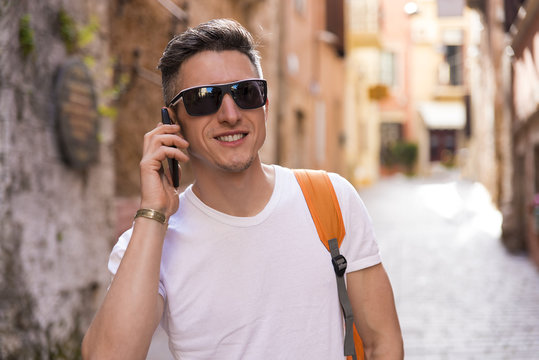 A young man walking around the old town and talking on the phone